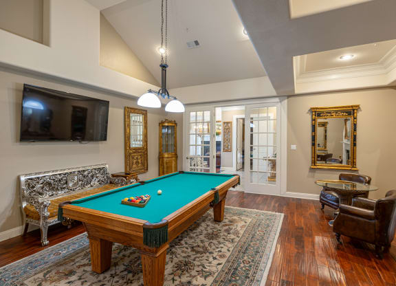 a living room with a pool table and a tv