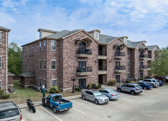 an apartment building with cars parked in a parking lot