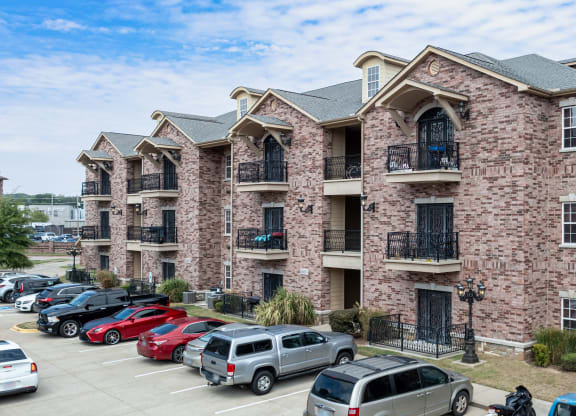 a brick apartment building with cars parked in the parking lot