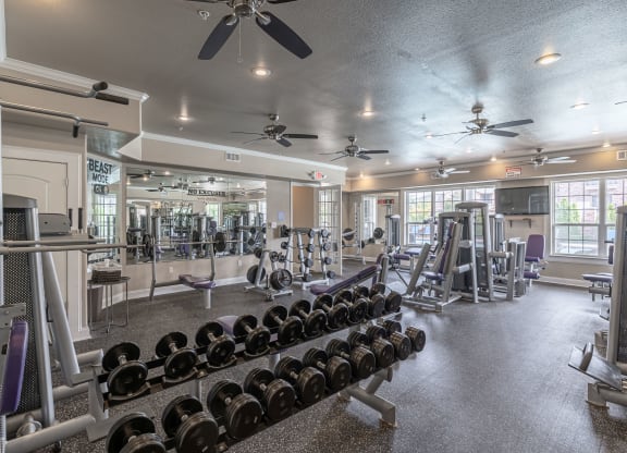 a gym with weights and cardio equipment and ceiling fans