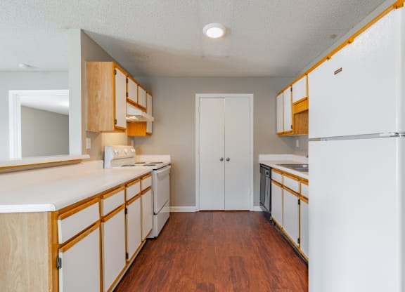 a kitchen with white counters and wooden cabinets and a refrigerator