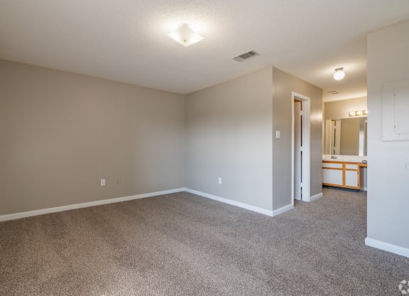 an empty living room with carpet and a door to a bathroom