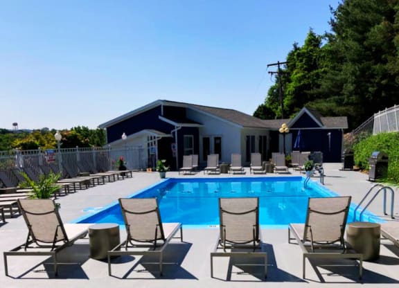 a swimming pool with deck chairs and a building in the background