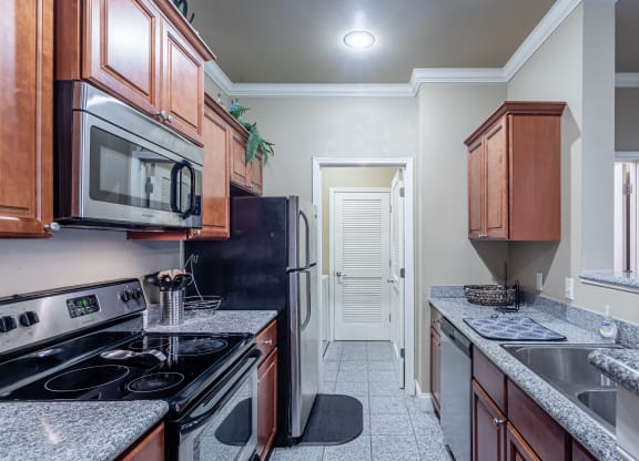 an empty kitchen with granite counter tops and a black stove and refrigerator