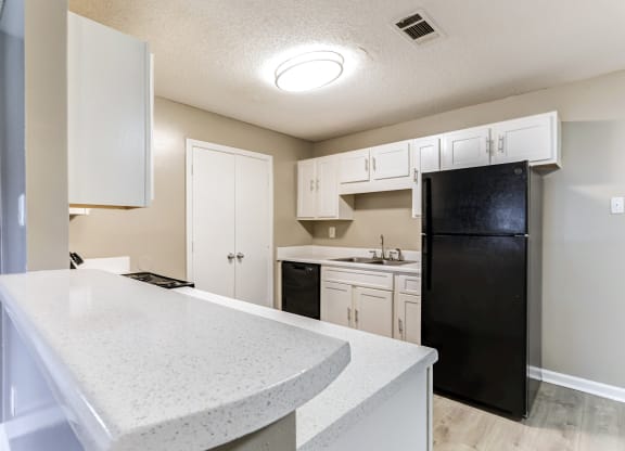 a kitchen with white cabinets and a black refrigerator