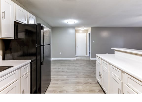 an empty kitchen with white cabinets and a black refrigerator