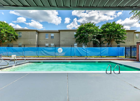 a swimming pool in front of a building with a blue fence