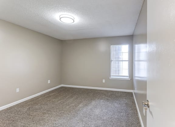 an empty room with carpet and a window