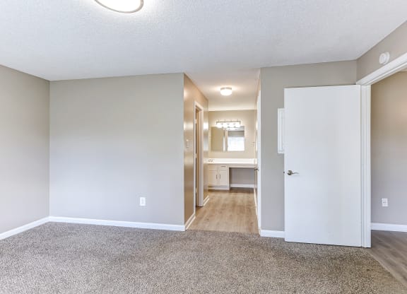 an empty living room and hallway with a door to a kitchen