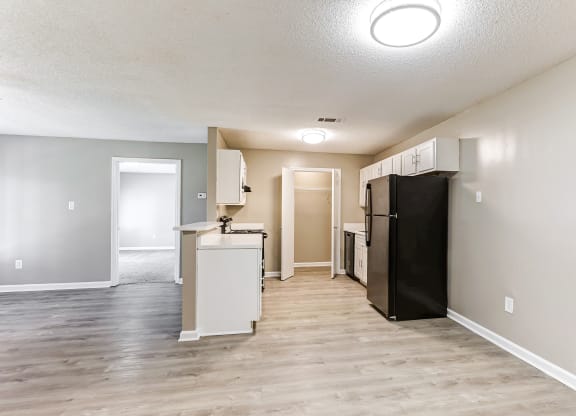 an empty room with a kitchen and a refrigerator