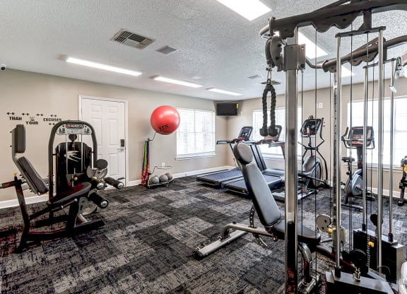 spacious gym with cardio machines and weights at the enclave at woodbridge apartments gym room