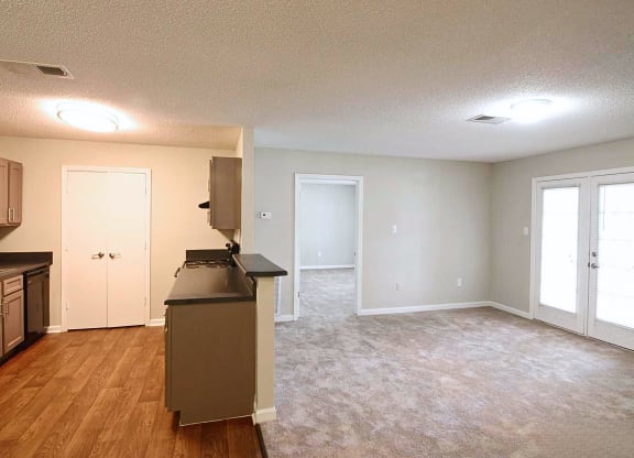 an empty kitchen and living room with a refrigerator and a sink