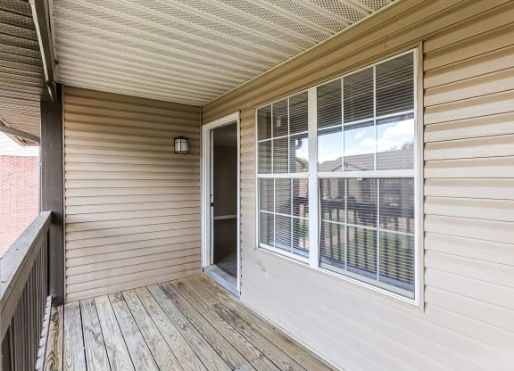 the deck of a home with a large window and a door