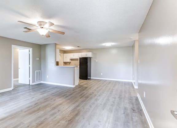 an empty living room and kitchen with a ceiling fan