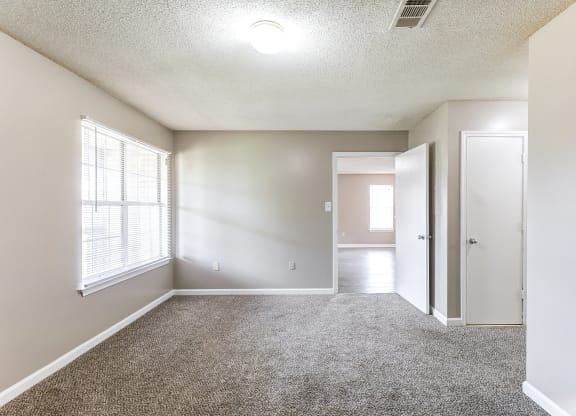 an empty living room with a large window and a door to a hallway