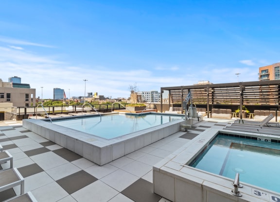 two hot tubs on the rooftop of a building with a city in the background
