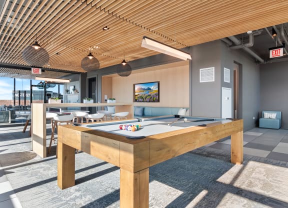 a pool table in a clubhouse with a bar in the background
