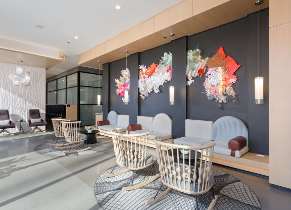 a lounge area with chairs and tables and artwork on the wall