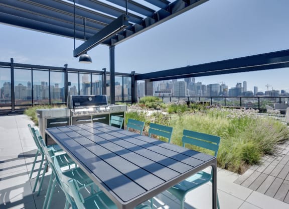 a table and chairs on a roof terrace with a grill and a view of the city