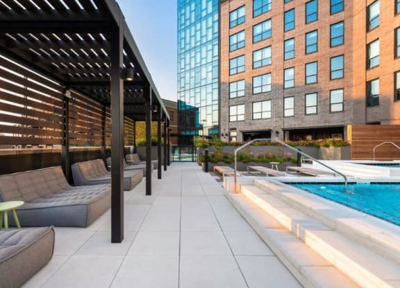 a pool with lounge chairs and a stool next to a building