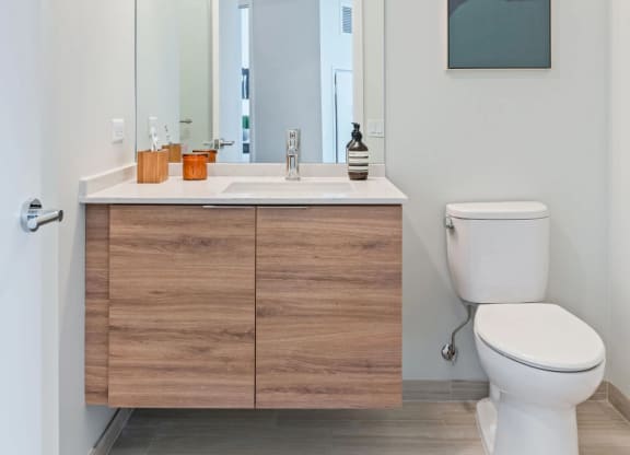 a bathroom with white walls and a wooden vanity with a white toilet