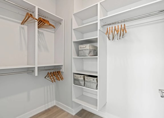 a walk in closet with white shelves and a white closet door