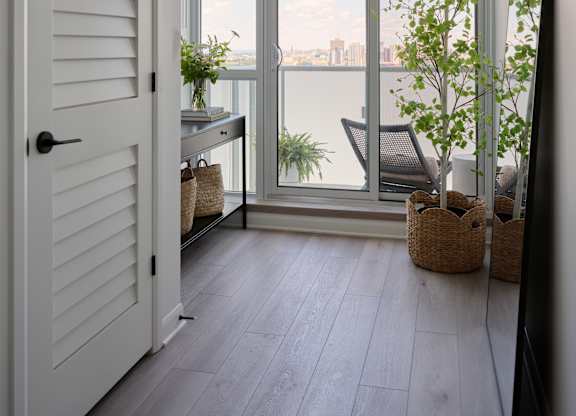 A white door opens to a balcony with a view of the city.