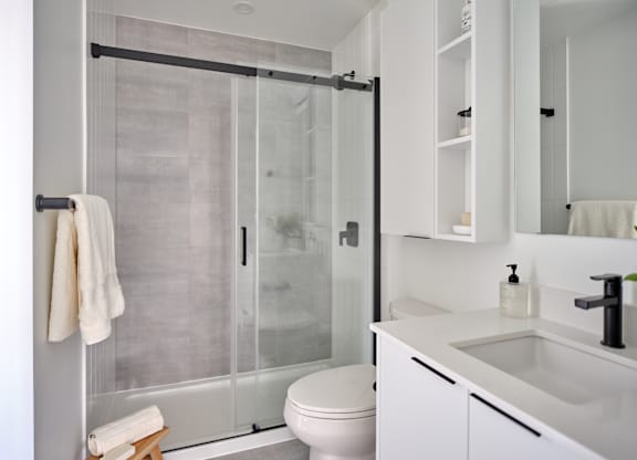 A white bathroom with a toilet, sink, and shower.