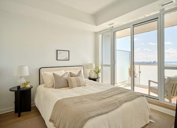 A bedroom with a large bed and a view of the ocean through the sliding glass doors.