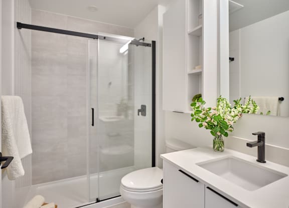 A white bathroom with a toilet, sink, and shower.