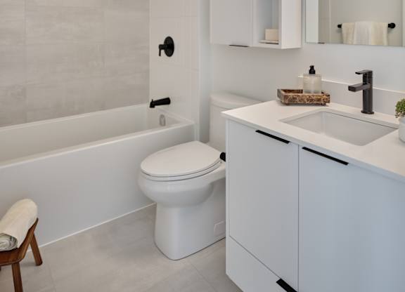 A white bathroom with a toilet, sink, and a chair.