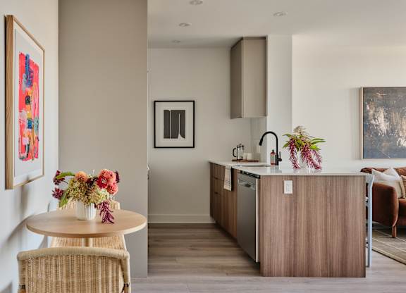 A modern kitchen with a wooden island and a dining table with chairs.
