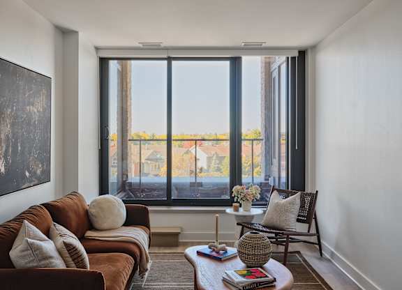A living room with a brown couch and a large window.