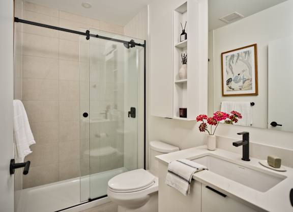 A white bathroom with a toilet, sink, and shower.
