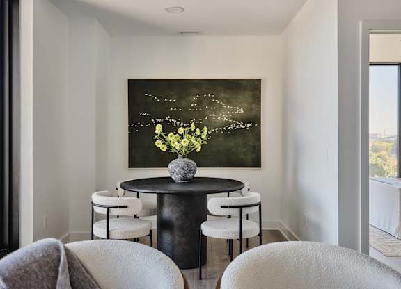 A painting of flowers is hanging on the wall above a table with chairs.