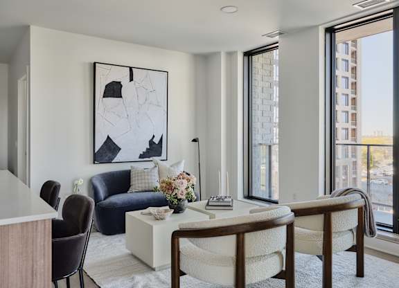 A modern living room with a blue sofa, a white coffee table, and a large abstract painting on the wall.
