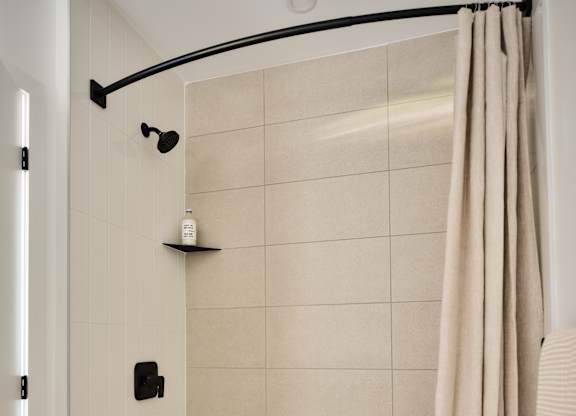 A white bathtub with a beige shower curtain.