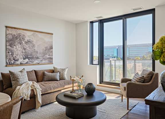 A living room with a large window and a painting on the wall.