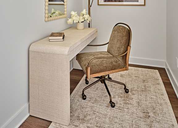 A beige desk with a chair and a lamp on it.