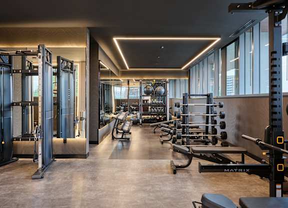A gym with a variety of equipment including a squat rack, bench, and weights.