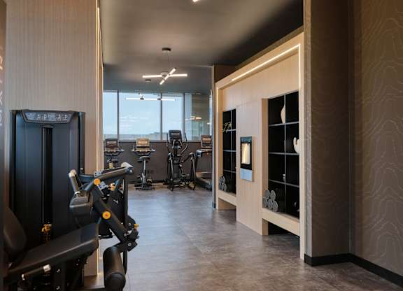 A gym with a row of treadmills and other exercise equipment.