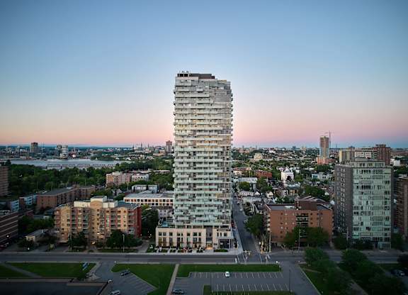 A tall, modern building stands in the middle of a cityscape at dusk.