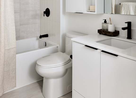 A white bathroom with a toilet, sink, and shower.