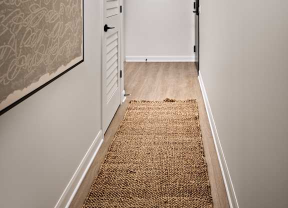 A hallway with a rug on the floor and a door on the right.