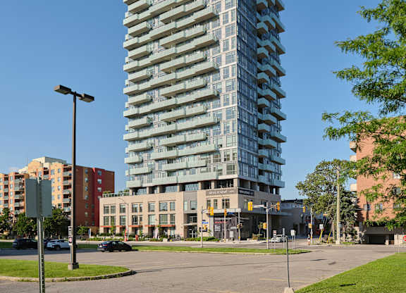 A tall, modern glass building stands in the middle of a city street.