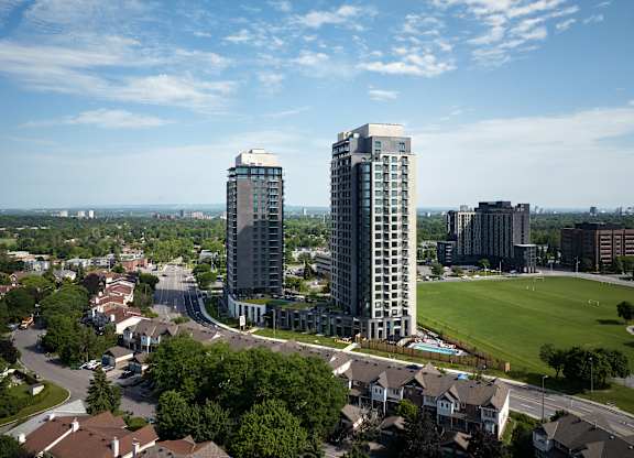 A cityscape with two tall buildings in the foreground and a park in the middle ground.