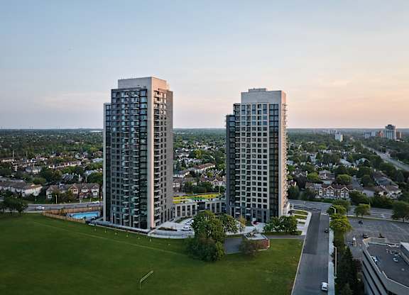 Two tall buildings are situated next to each other with a pool in the middle.