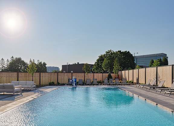 A sunny day at the pool with sun loungers and a blue sky.