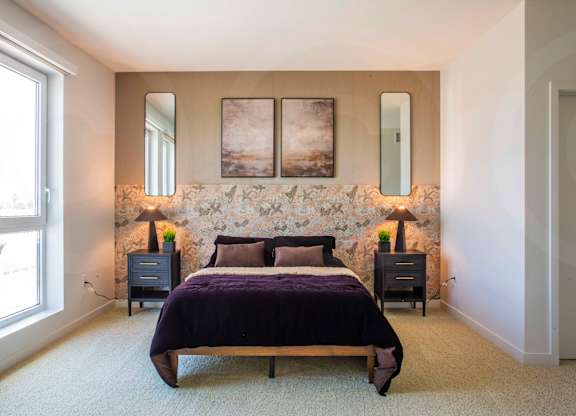 A bedroom with a bed, two nightstands, and a stone wall.