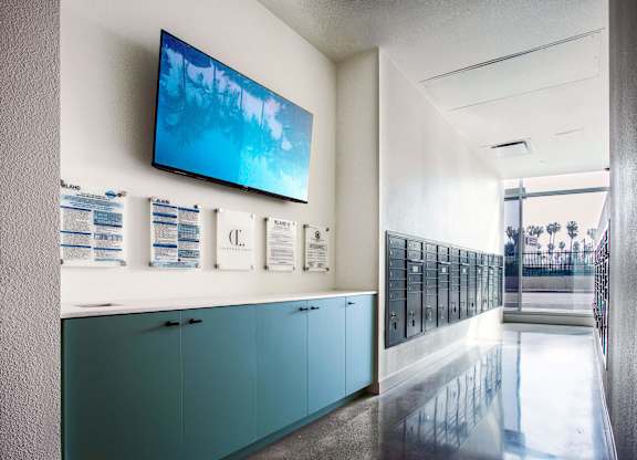 A hallway with a row of lockers and a TV mounted on the wall.